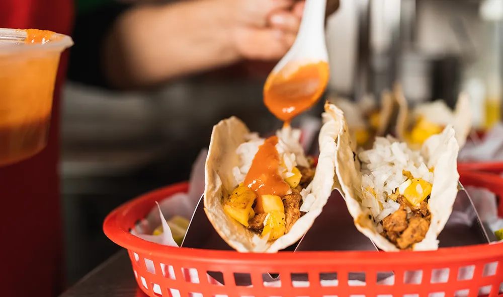persona añadiendo salsas Goya a tacos